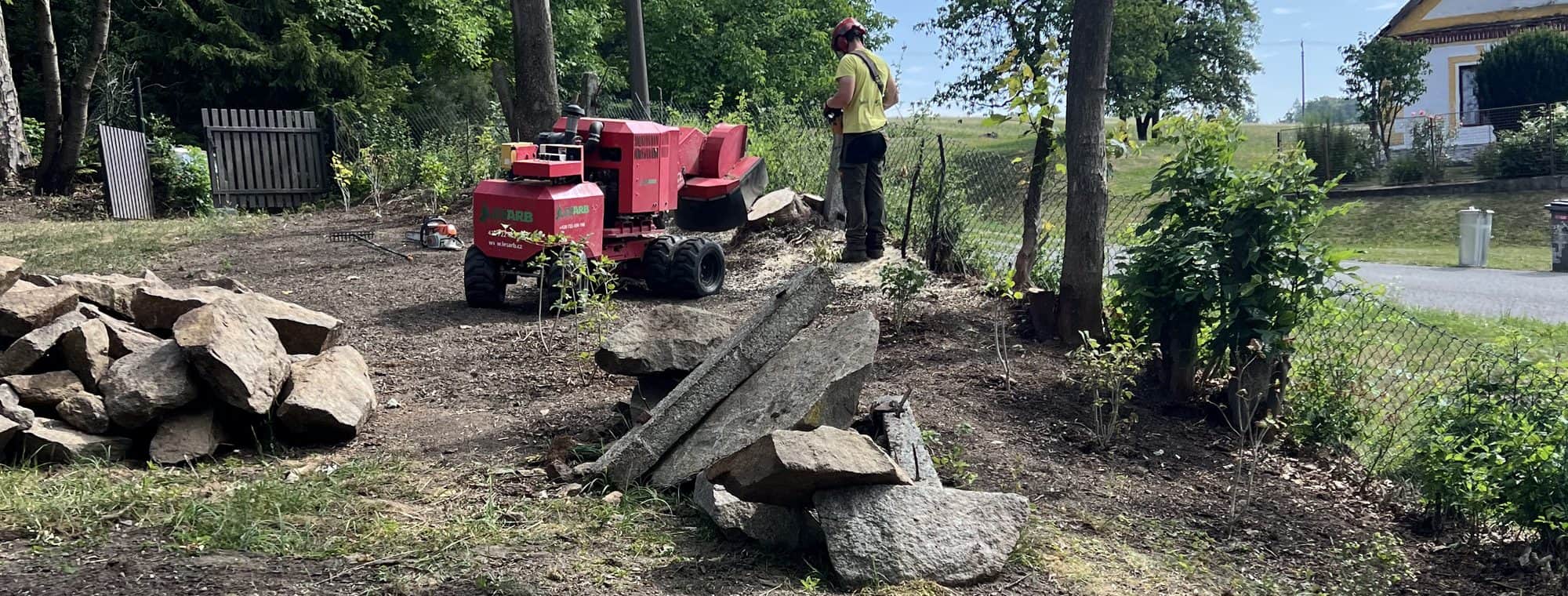Uklizený pozemek po odfrézování pařezů, vzadu stroj a srovnaná hlína