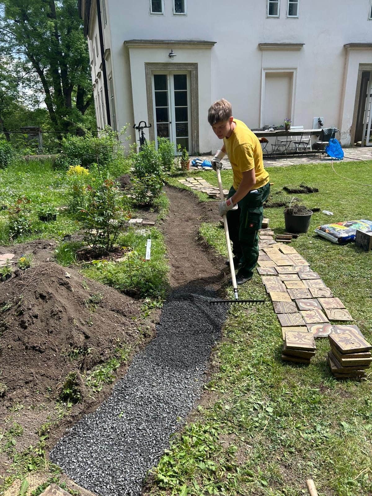 Rozdělaná cesta vedoucí k domu, vedle hromada zeminy