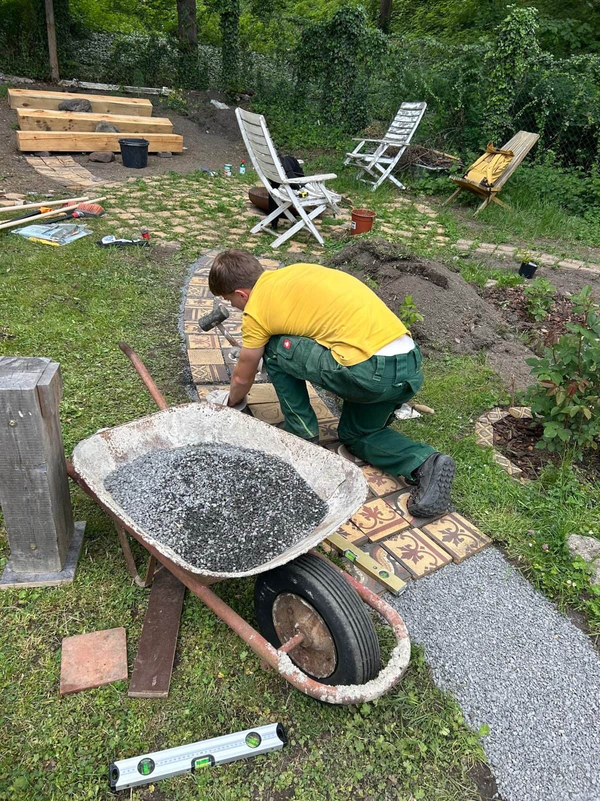 Zahradník s kolečkem štěrku u rozestavěné cesty