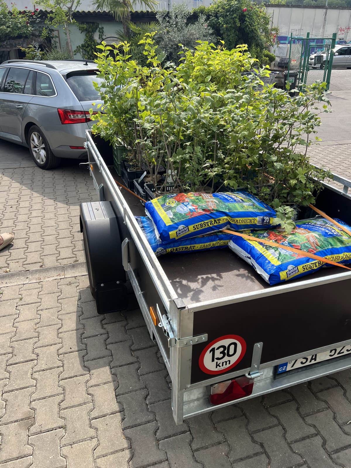 Přívěsný vozík s pytli substrátu zapřažený za autem